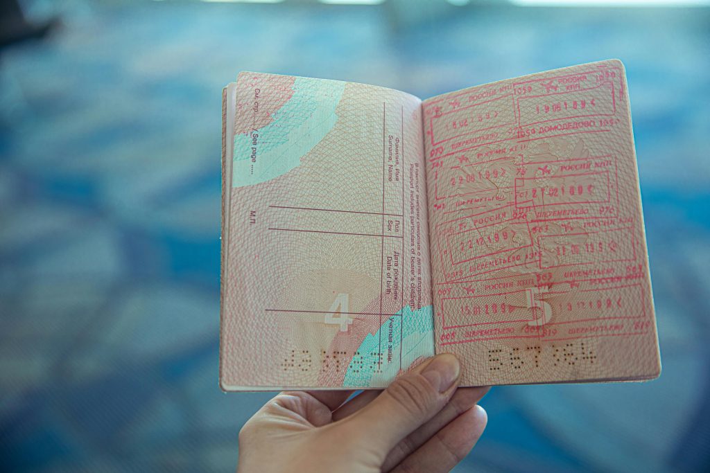 pexels photo 4922356 4922356 1 Close-up view of an open passport displaying various travel stamps in an airport setting.