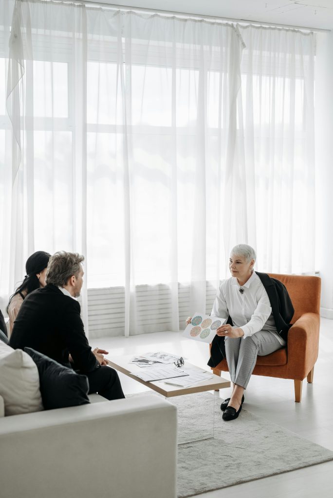 Three adults in a modern minimalist room engaged in a consultation meeting.